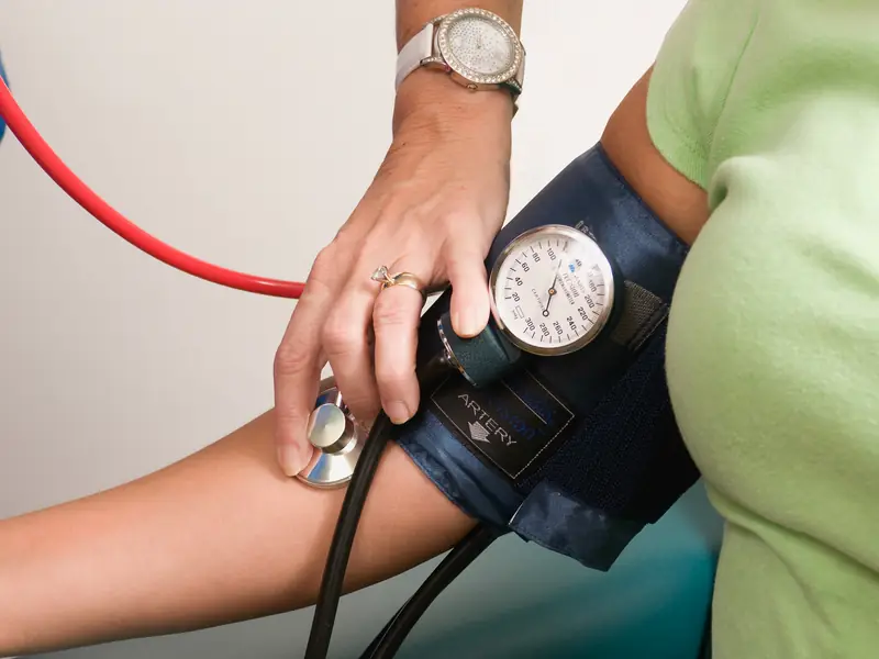 Profissional de saúde aferindo a pressão arterial de um trabalhador durante um exame.