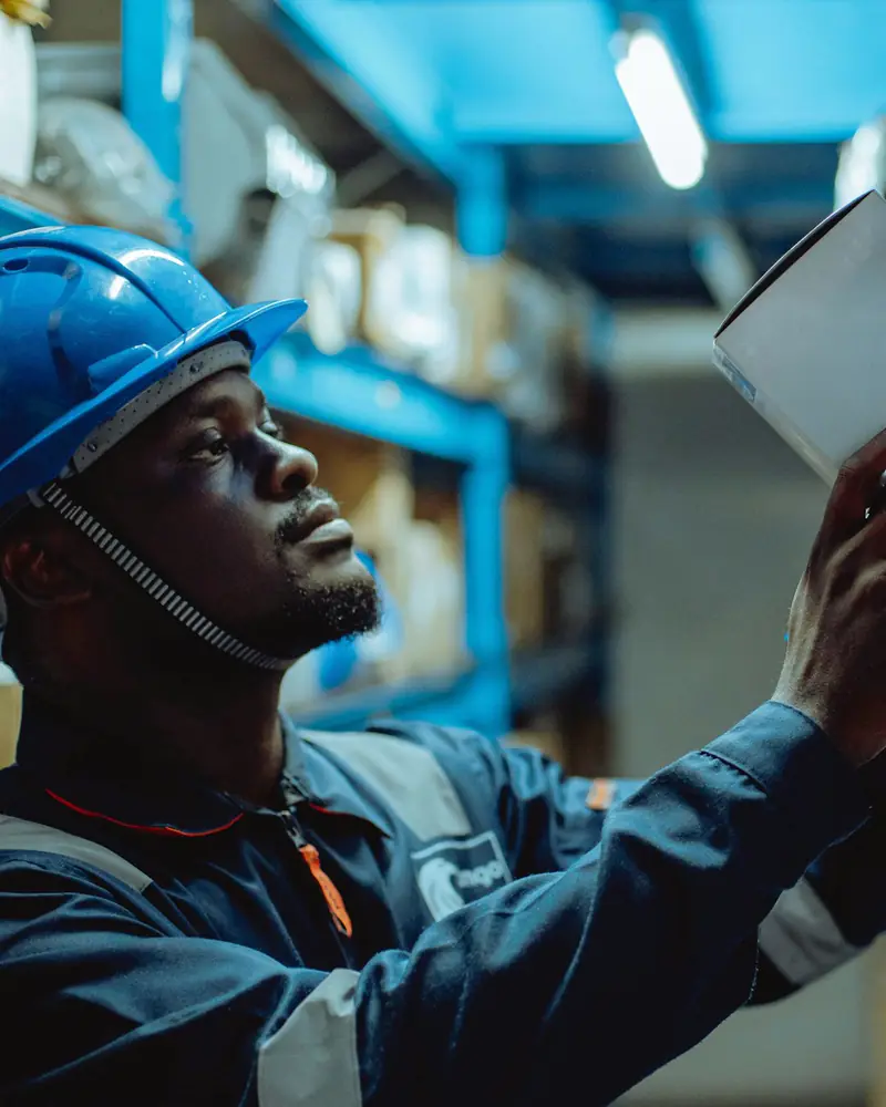 Profissional de segurança do trabalho, de capacete, fazendo uma inspeção em um galpão.